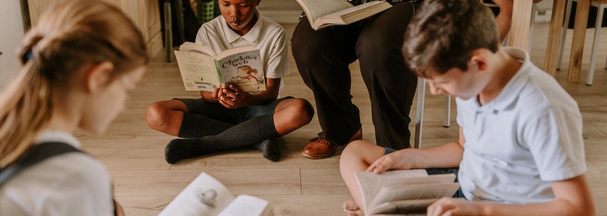 A boy reading Charlotte’s Web on the classroom floor