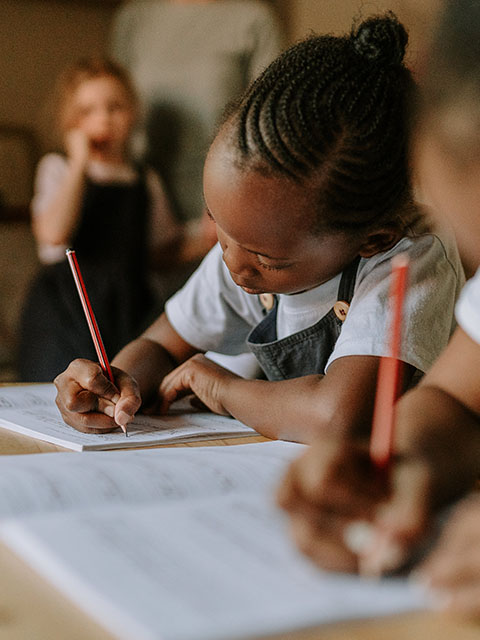 A child writing in class at Three Peaks School